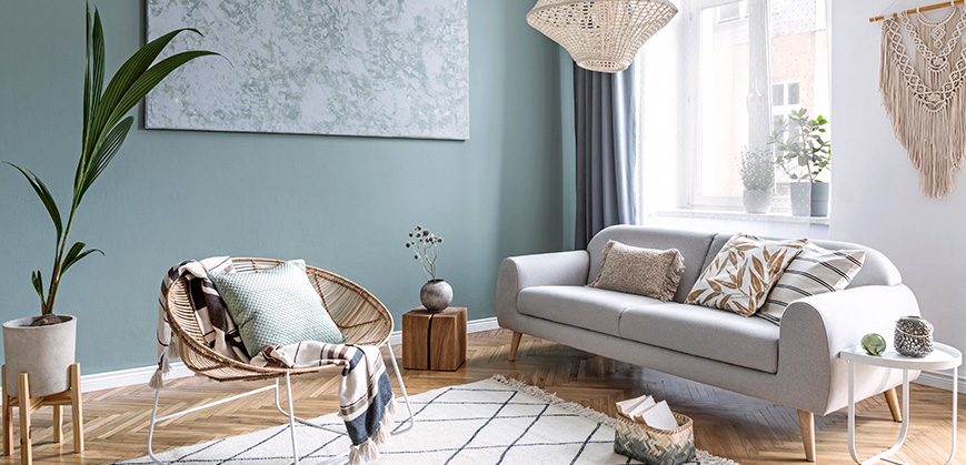 Sitzecke aus beigem Sofa und Rattan Sessel Gemütliche Sitzecke aus beigem Sofa und Rattan Sessel mit vielen Kissen und Boho-Deko