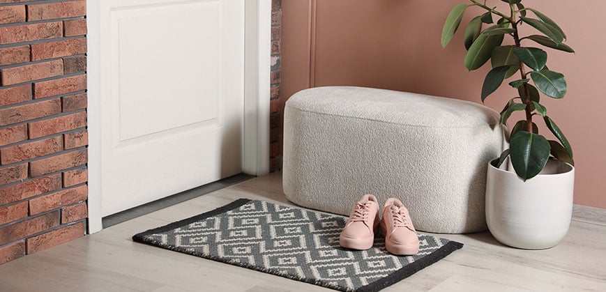 Kleiner Hocker neben Eingangstür und vor einer rosa Wand