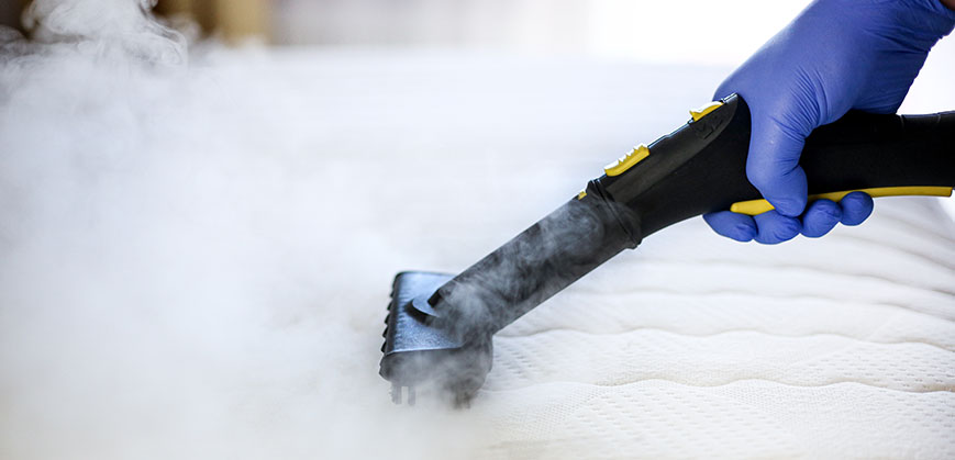 Matratze wird mit einem Dampfreiniger gesäubert
