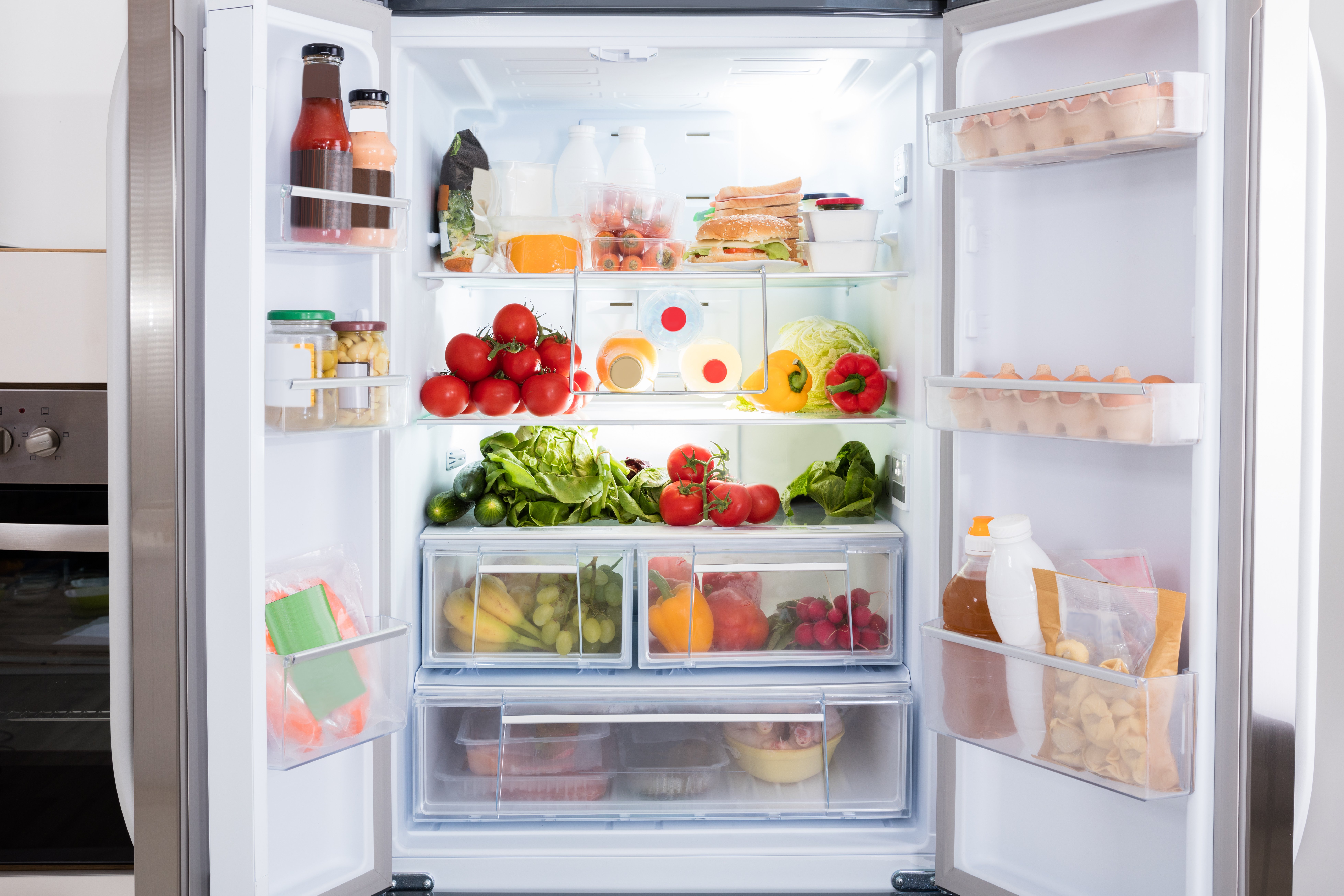 Ein vollgepackter Kühlschrank steht offen in der Küche.