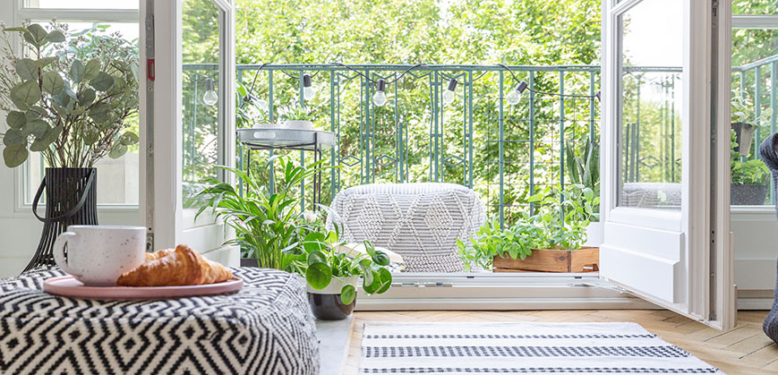 Blick aus dem Wohnzimmer auf einen kleinen Balkon mit vielen Pflanzen