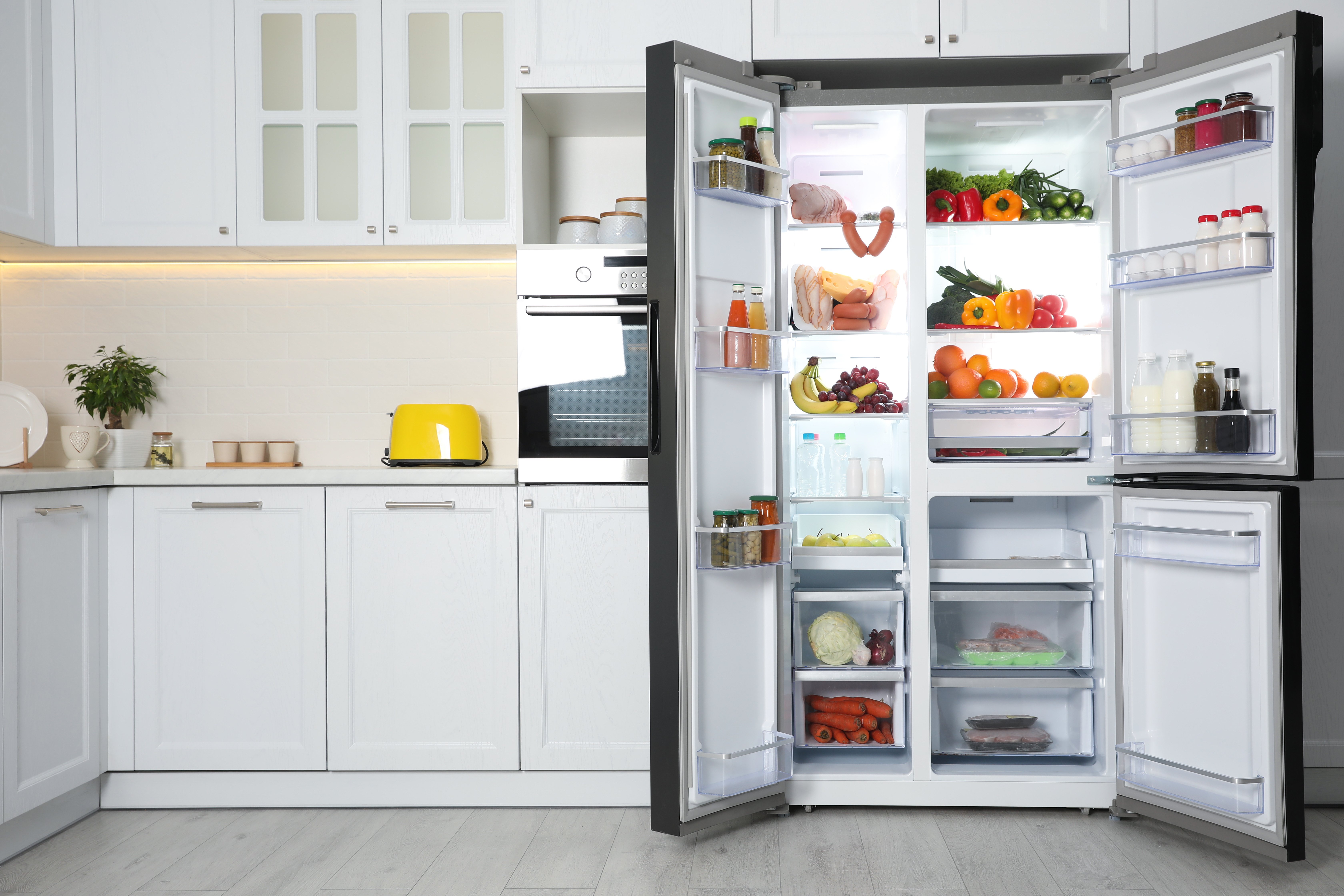 Ein großer Kühlschrank mit Gefrierfach steht mit offenen Türen in der Küche.