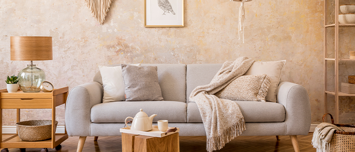 Beiges 2-Sitzer Sofa mit hellen Kissen und Decken in einem gemütlichen Boho-Wohnzimmer