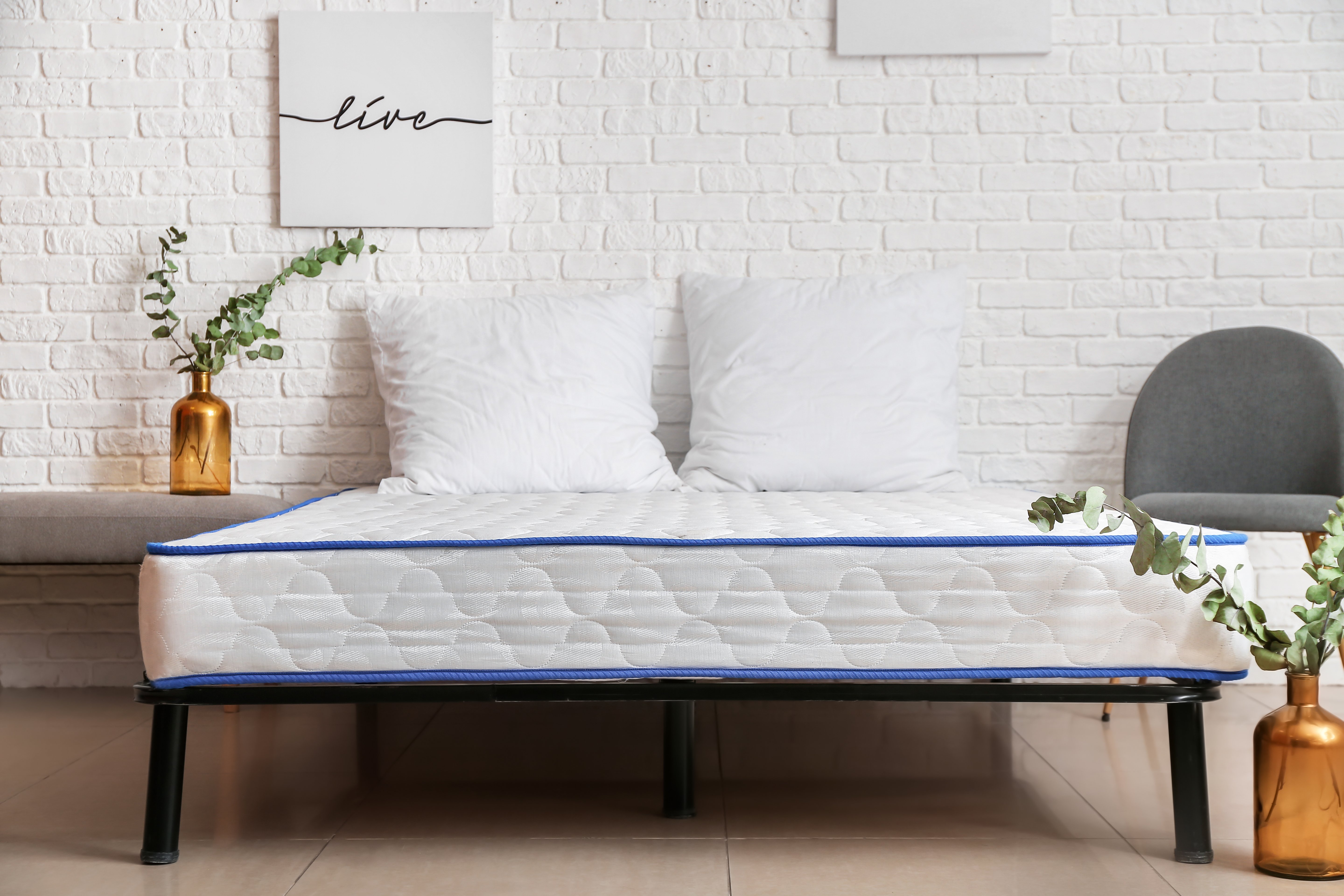 Auf einem Bett liegt eine weiße Matratze und zwei weiße Kopfkissen.