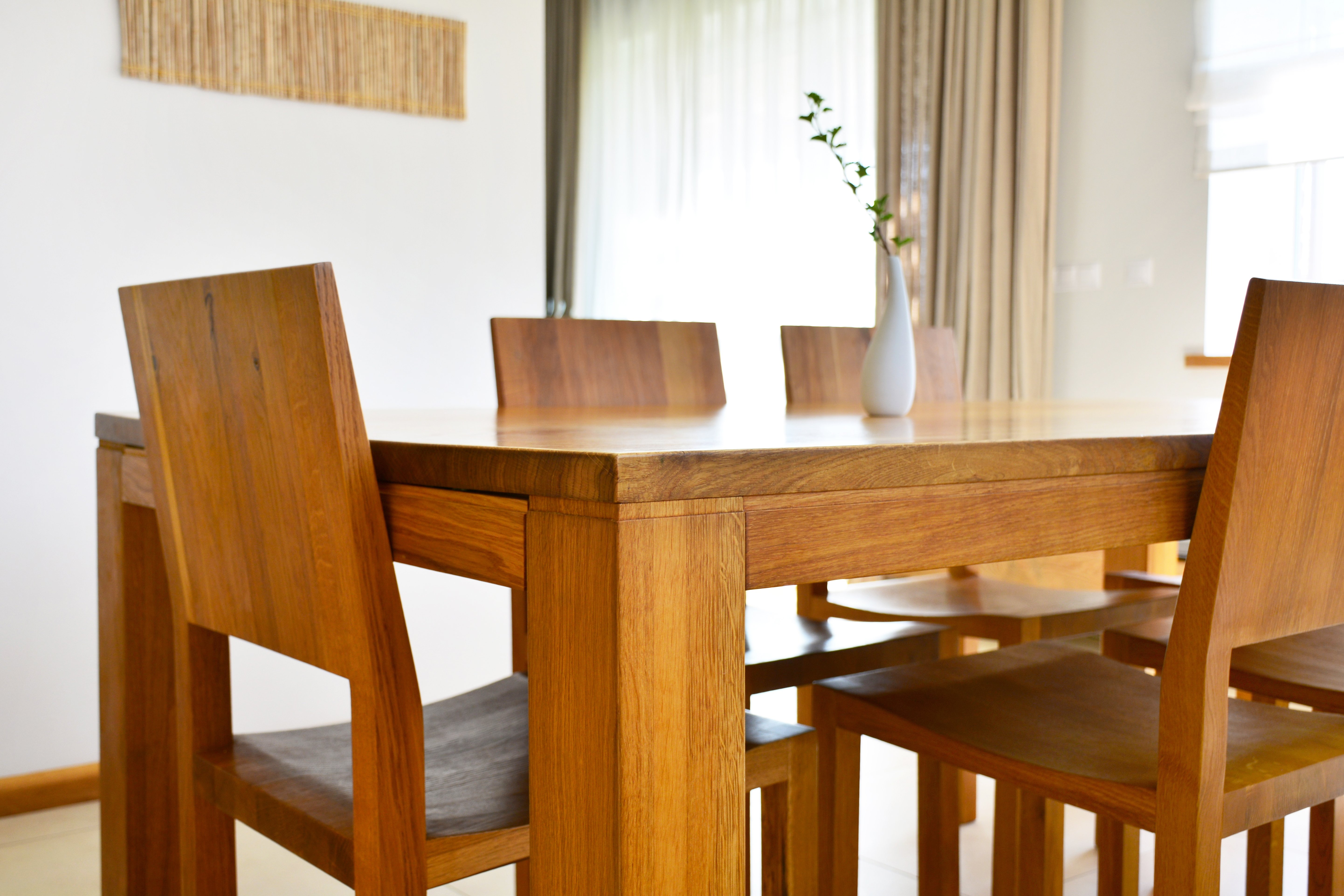 Ein Holzesstisch mit den passenden Stühlen stehen im Esszimmer. Auf dem Tisch ist eine Vase platziert.