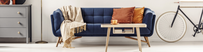 Dunkelblaues Sofa mit Couchtisch aus hellem Holz und gemütlichen Heimtextilien